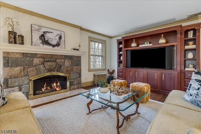 living room with crown molding, radiator, a fireplace, and wood finished floors