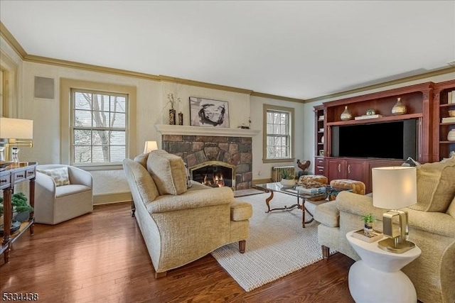 living area featuring wood finished floors, a fireplace, baseboards, and ornamental molding