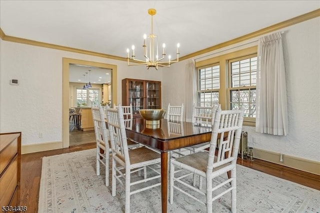 dining room with an inviting chandelier, wood finished floors, baseboards, and ornamental molding