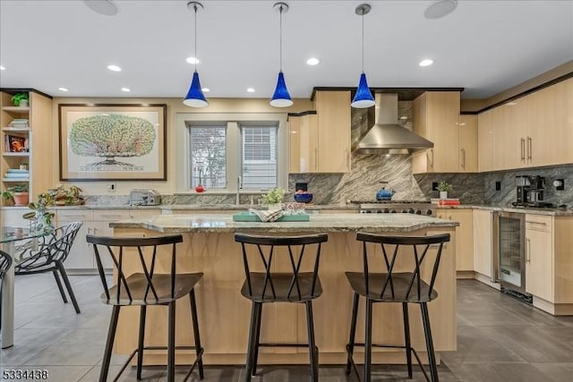 kitchen featuring wall chimney range hood, beverage cooler, and light brown cabinets