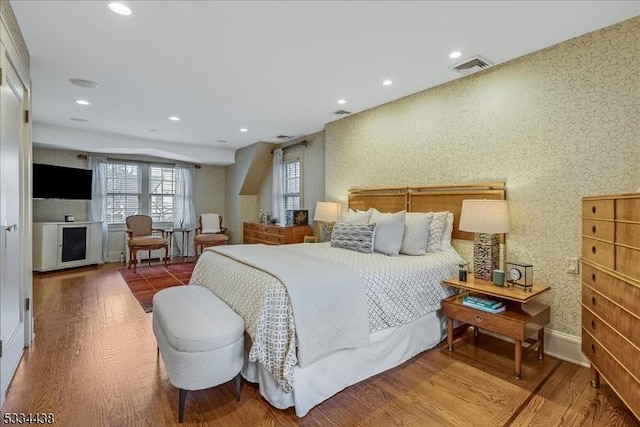 bedroom with visible vents, recessed lighting, wallpapered walls, and wood finished floors