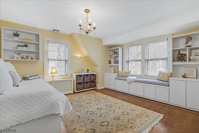 bedroom with radiator heating unit, wood finished floors, visible vents, and a chandelier