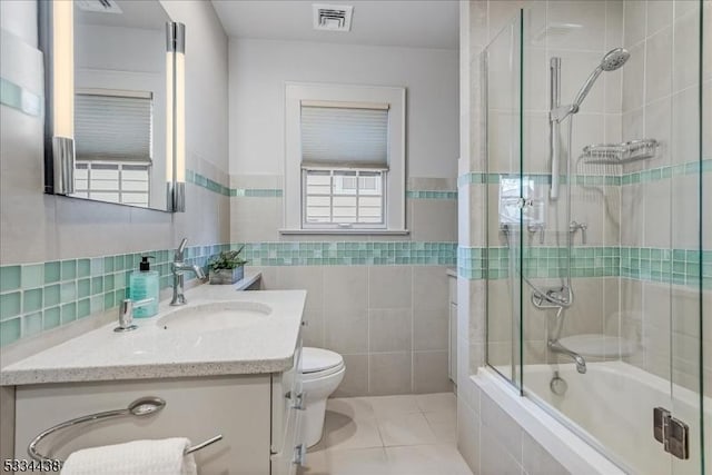 bathroom featuring vanity, visible vents, tile walls, tiled shower / bath, and tile patterned floors