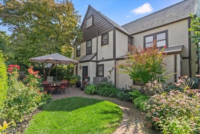 rear view of house featuring a patio, a lawn, and stucco siding