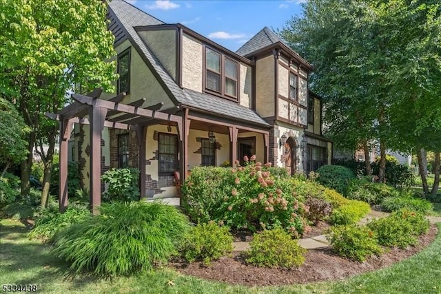 tudor-style house featuring a pergola and stucco siding