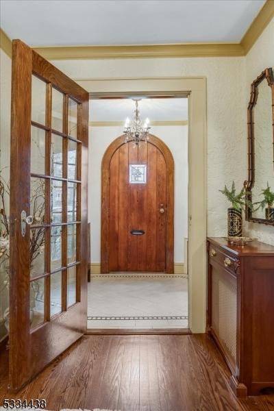 doorway to outside featuring hardwood / wood-style floors, a chandelier, and ornamental molding