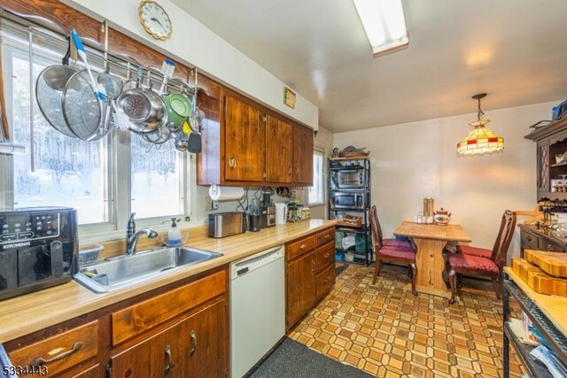 kitchen with sink, white dishwasher, and decorative light fixtures