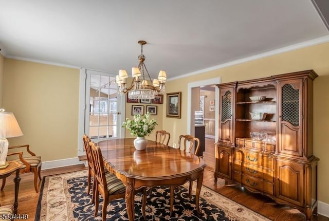 dining room with a notable chandelier, hardwood / wood-style flooring, and ornamental molding