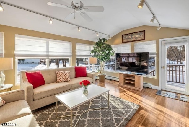 living room with vaulted ceiling, a wealth of natural light, and baseboard heating