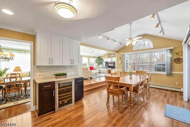 kitchen with lofted ceiling, white cabinetry, a baseboard radiator, beverage cooler, and decorative backsplash