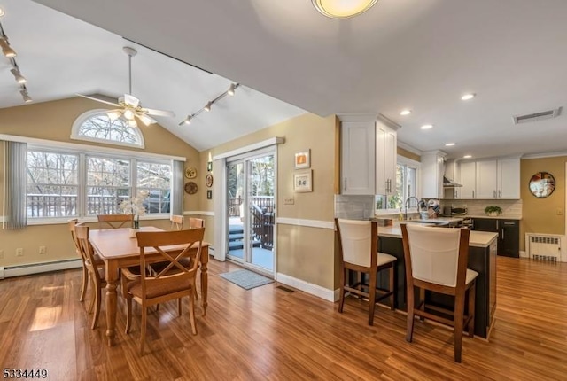 dining area featuring lofted ceiling, a baseboard radiator, radiator heating unit, ceiling fan, and light hardwood / wood-style floors