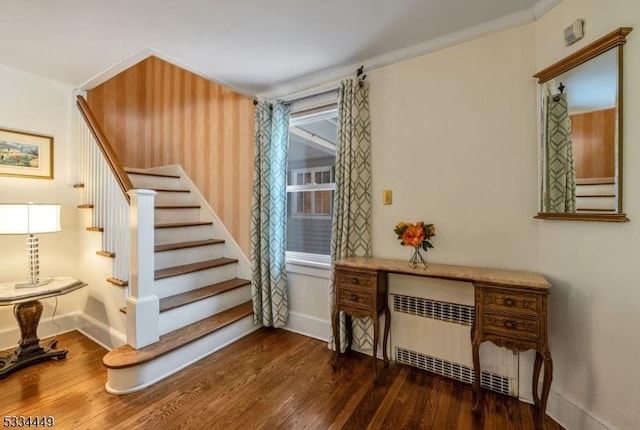 stairway featuring hardwood / wood-style flooring, crown molding, and radiator heating unit