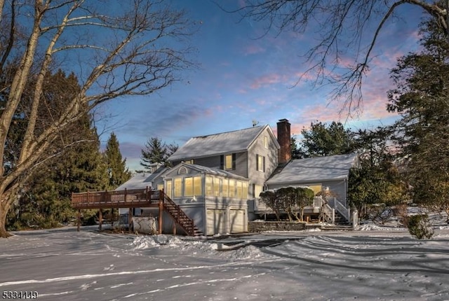 snow covered property featuring a wooden deck and a sunroom