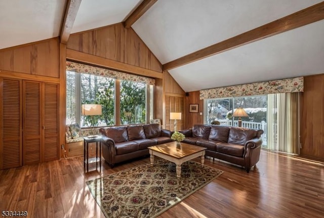 living room featuring plenty of natural light, lofted ceiling with beams, wood-type flooring, and wood walls