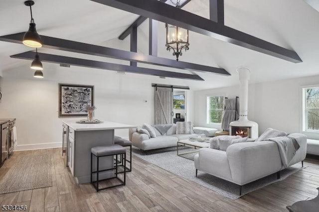 living room with hardwood / wood-style flooring, a barn door, plenty of natural light, and lofted ceiling with beams