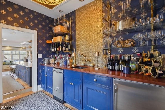 bar with dishwasher, blue cabinetry, sink, and refrigerator