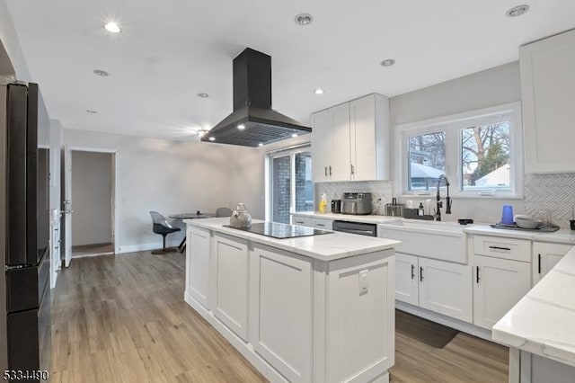 kitchen with sink, white cabinetry, island range hood, a kitchen island, and black appliances