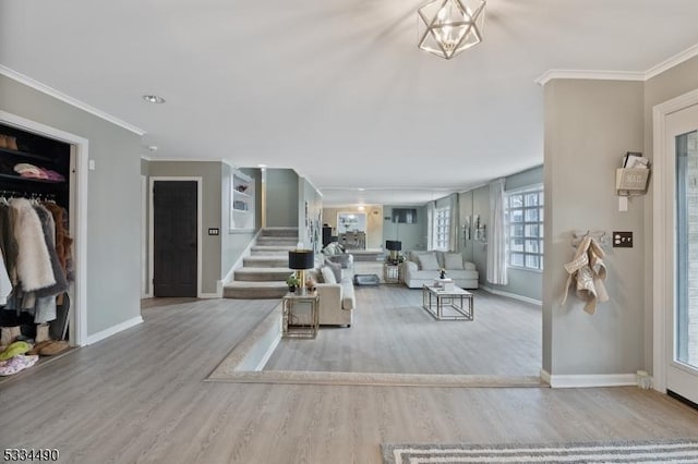 living room featuring crown molding, light hardwood / wood-style flooring, and a notable chandelier