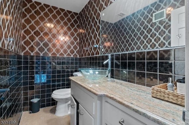 bathroom featuring vanity, toilet, and tile walls