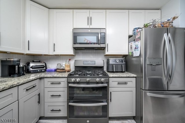 kitchen featuring stainless steel appliances, backsplash, white cabinets, and light stone counters