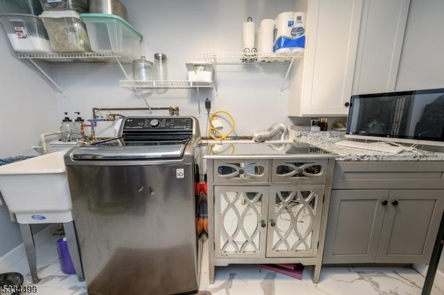 kitchen with washer / clothes dryer, light stone countertops, and gray cabinetry