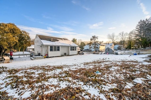 snow covered house featuring a storage unit