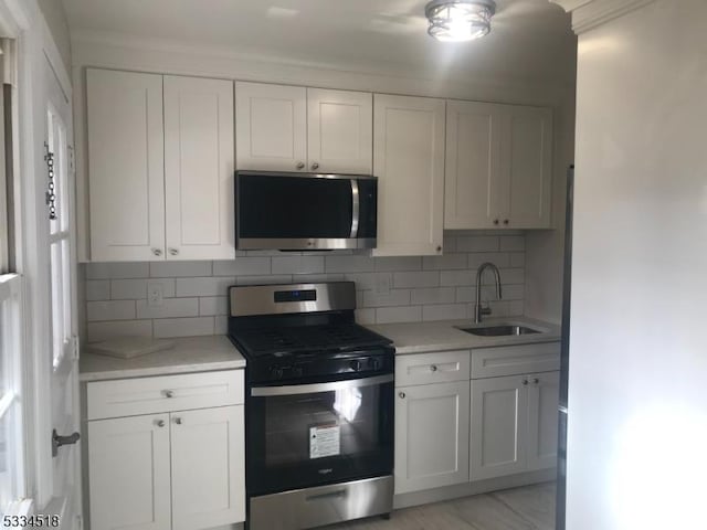 kitchen with white cabinetry, sink, backsplash, and appliances with stainless steel finishes