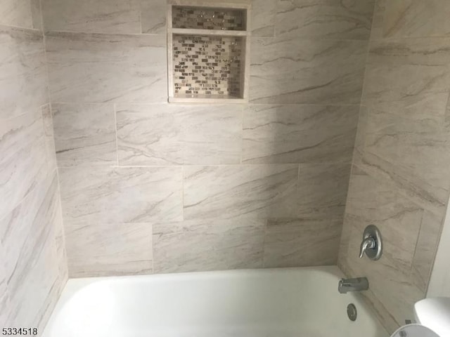 bathroom featuring tiled shower / bath combo and toilet