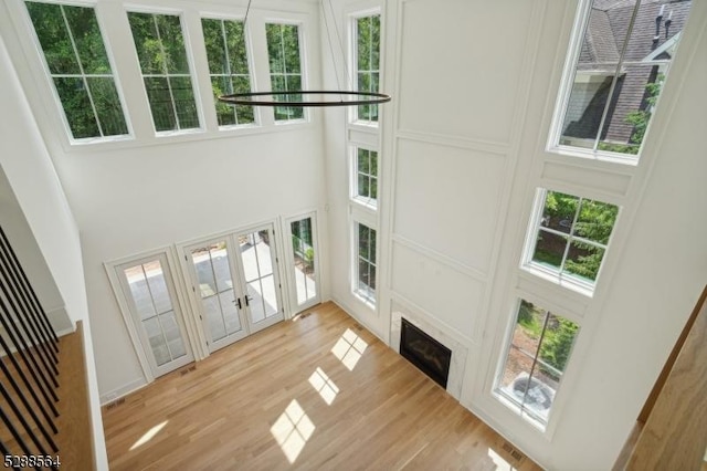 living room featuring light hardwood / wood-style flooring, plenty of natural light, french doors, and a towering ceiling