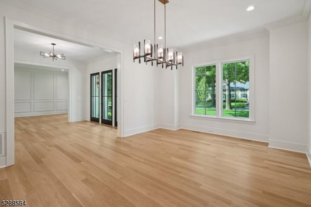 unfurnished dining area with crown molding, a notable chandelier, and light hardwood / wood-style flooring