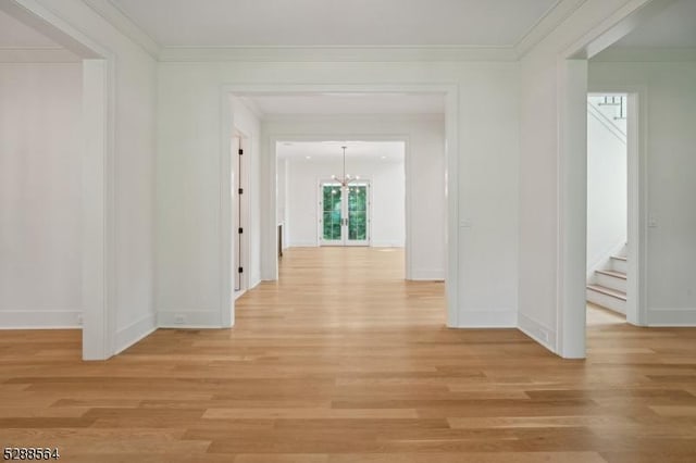 hall featuring light wood-type flooring, a chandelier, and crown molding