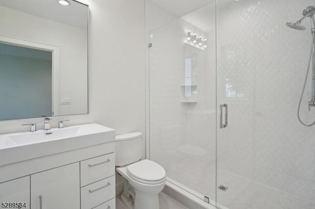 bathroom featuring toilet, vanity, and a shower with shower door