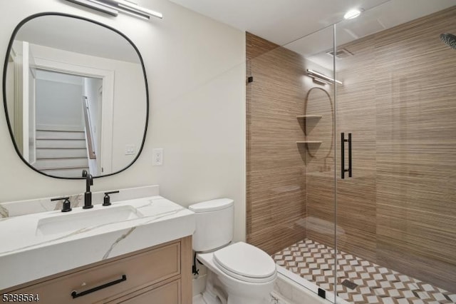 bathroom with toilet, vanity, and a shower with shower door