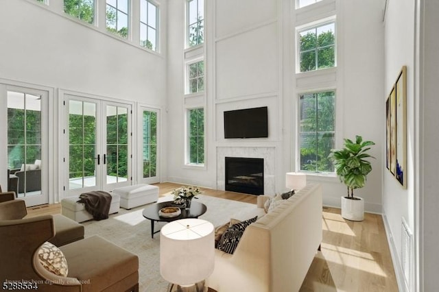 living room with light hardwood / wood-style flooring, a high ceiling, and french doors