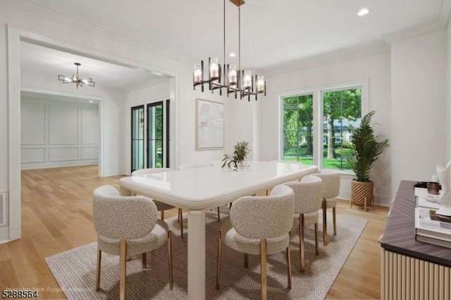 dining room featuring ornamental molding, light wood-type flooring, and a chandelier