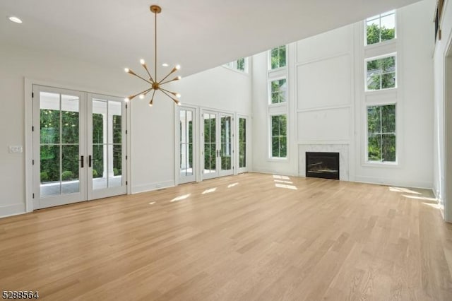 unfurnished living room with light wood-type flooring, french doors, and a healthy amount of sunlight