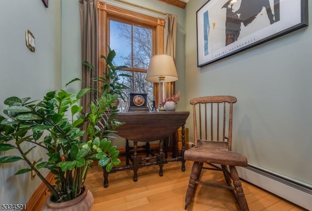 sitting room with a baseboard heating unit and hardwood / wood-style floors