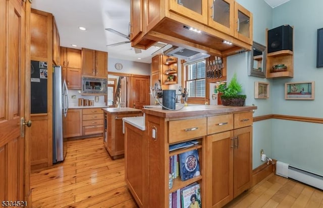 kitchen with light hardwood / wood-style floors, a baseboard heating unit, stainless steel appliances, and a center island