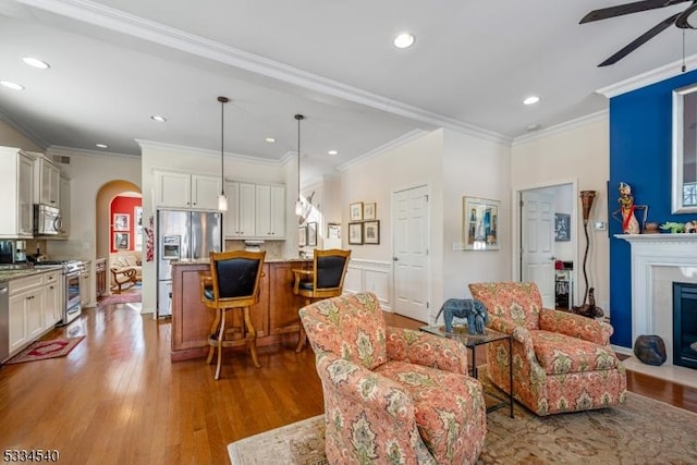 living room featuring wood-type flooring, ornamental molding, and ceiling fan