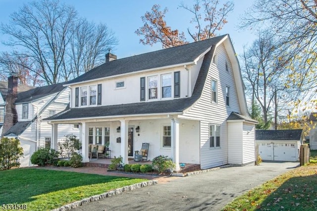 view of front of house with a garage, an outdoor structure, covered porch, and a front yard