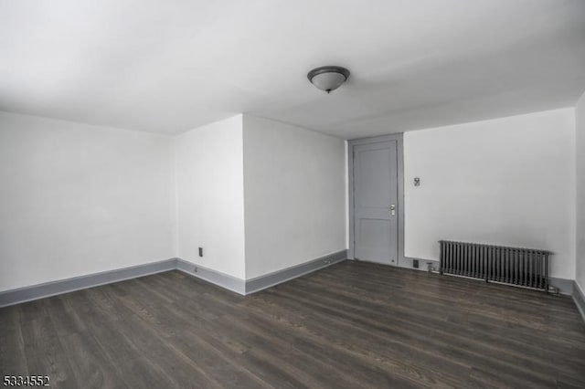 additional living space with radiator and dark wood-type flooring