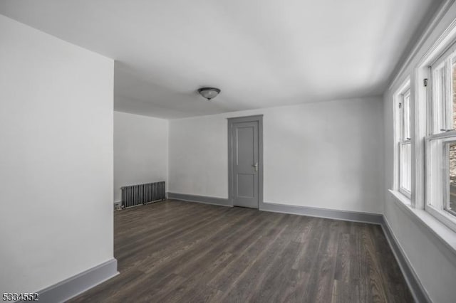 empty room featuring radiator and dark hardwood / wood-style flooring