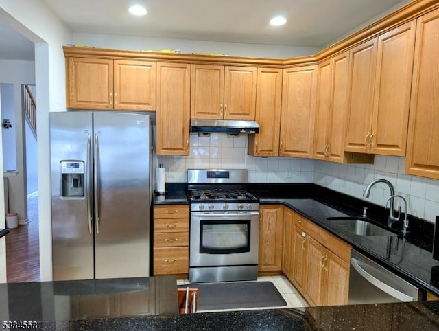 kitchen with tasteful backsplash, stainless steel appliances, sink, and dark stone countertops