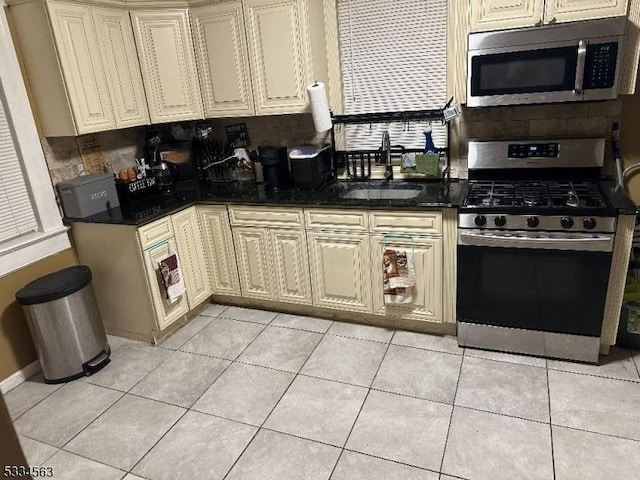 kitchen featuring cream cabinets, appliances with stainless steel finishes, sink, and light tile patterned floors