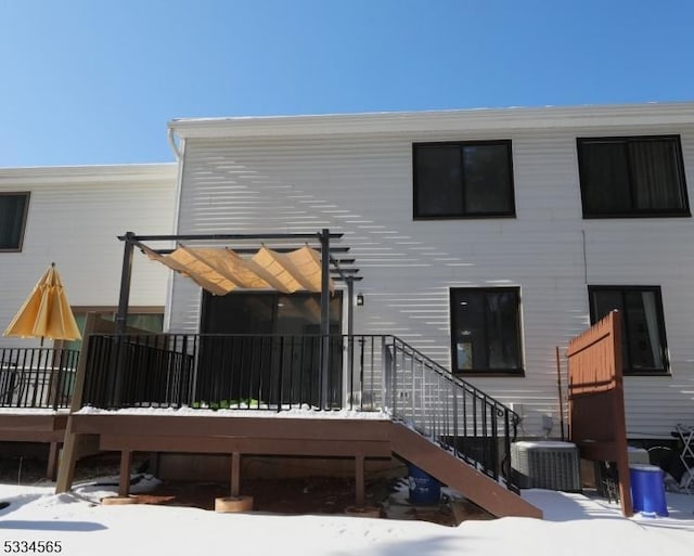 snow covered property featuring central AC unit, a pergola, and a wooden deck