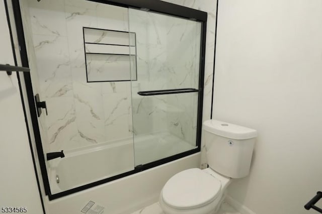 bathroom featuring toilet and bath / shower combo with glass door