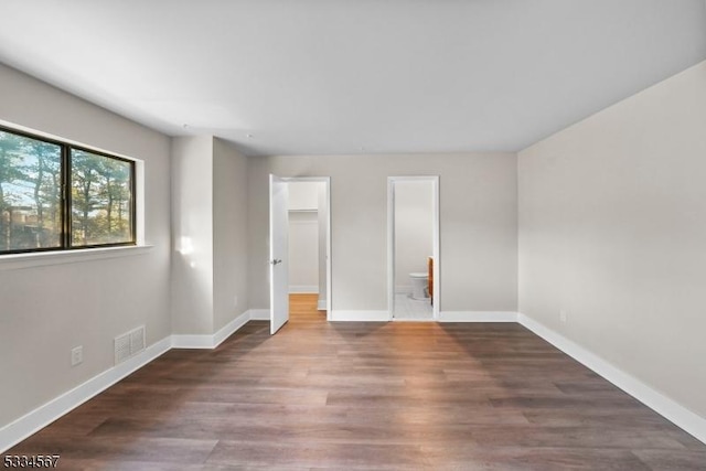 unfurnished bedroom with ensuite bath and dark hardwood / wood-style flooring