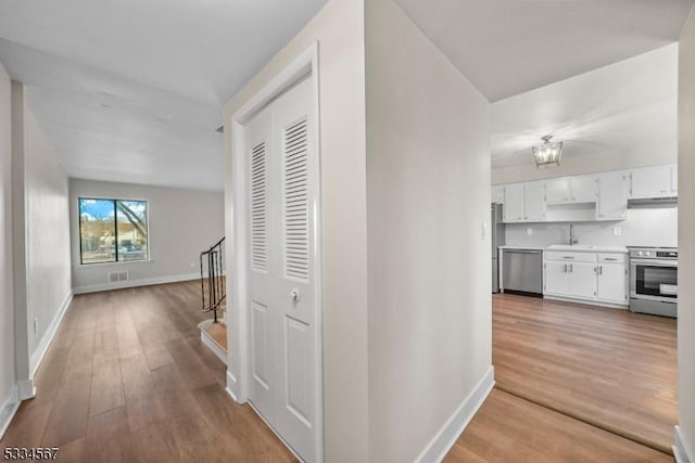 corridor with sink and light hardwood / wood-style flooring