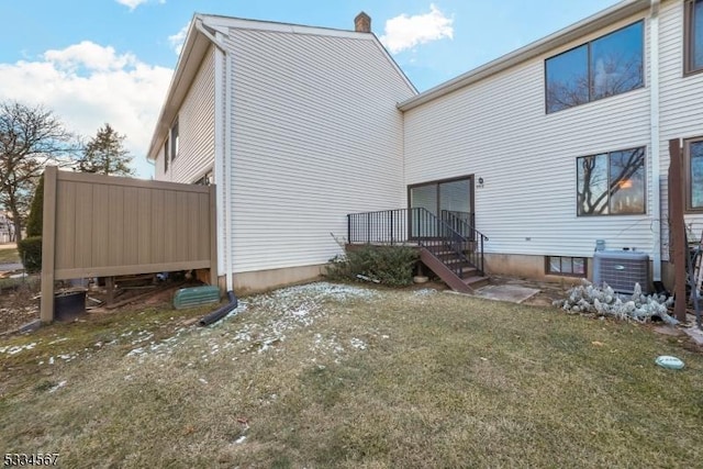 back of property with central AC unit and a lawn