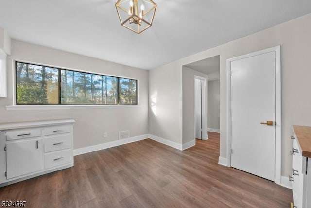 unfurnished bedroom featuring a notable chandelier and dark hardwood / wood-style flooring